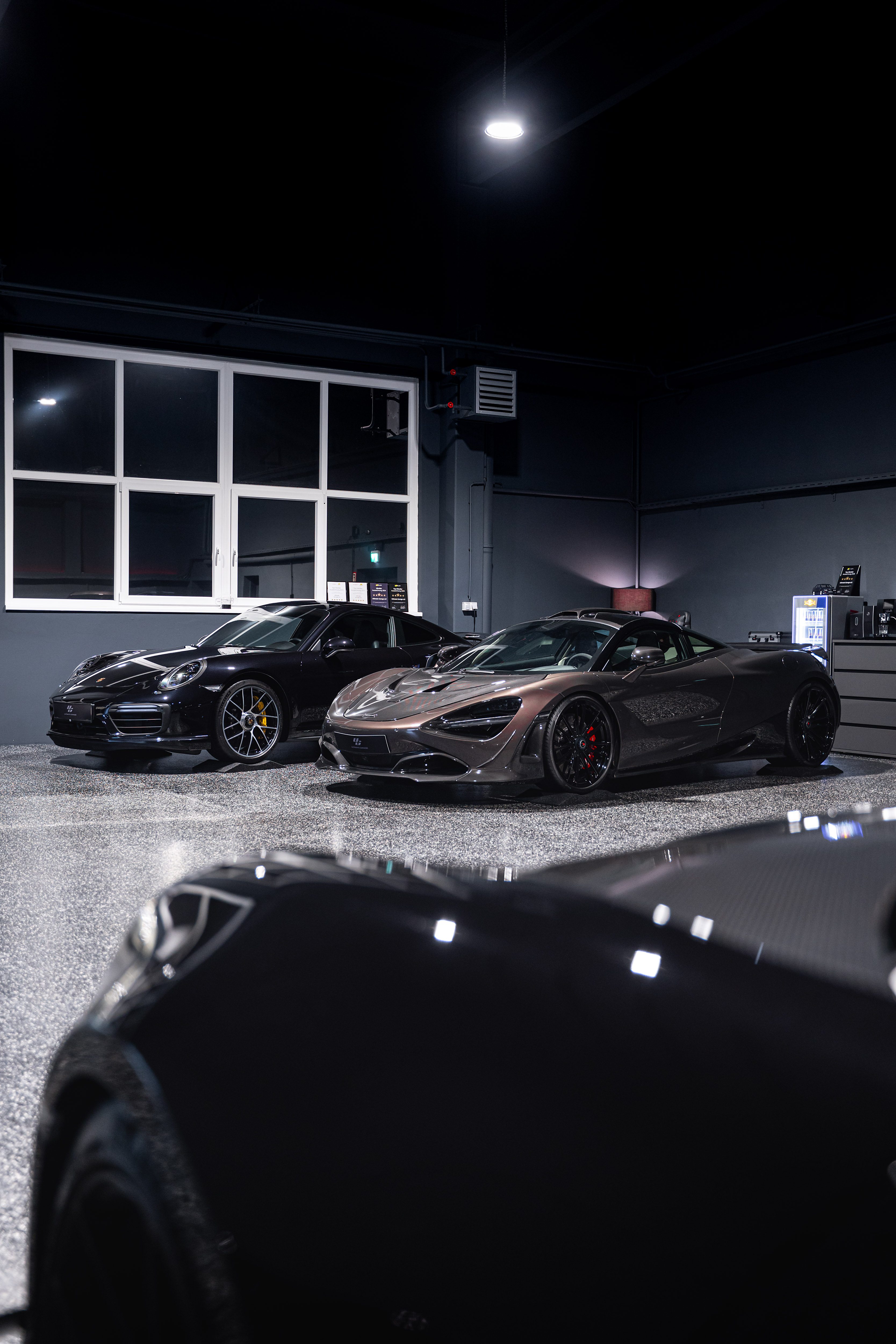 Porsche 911 Turbo S and McLaren 720S in the Ultimate Garage showroom