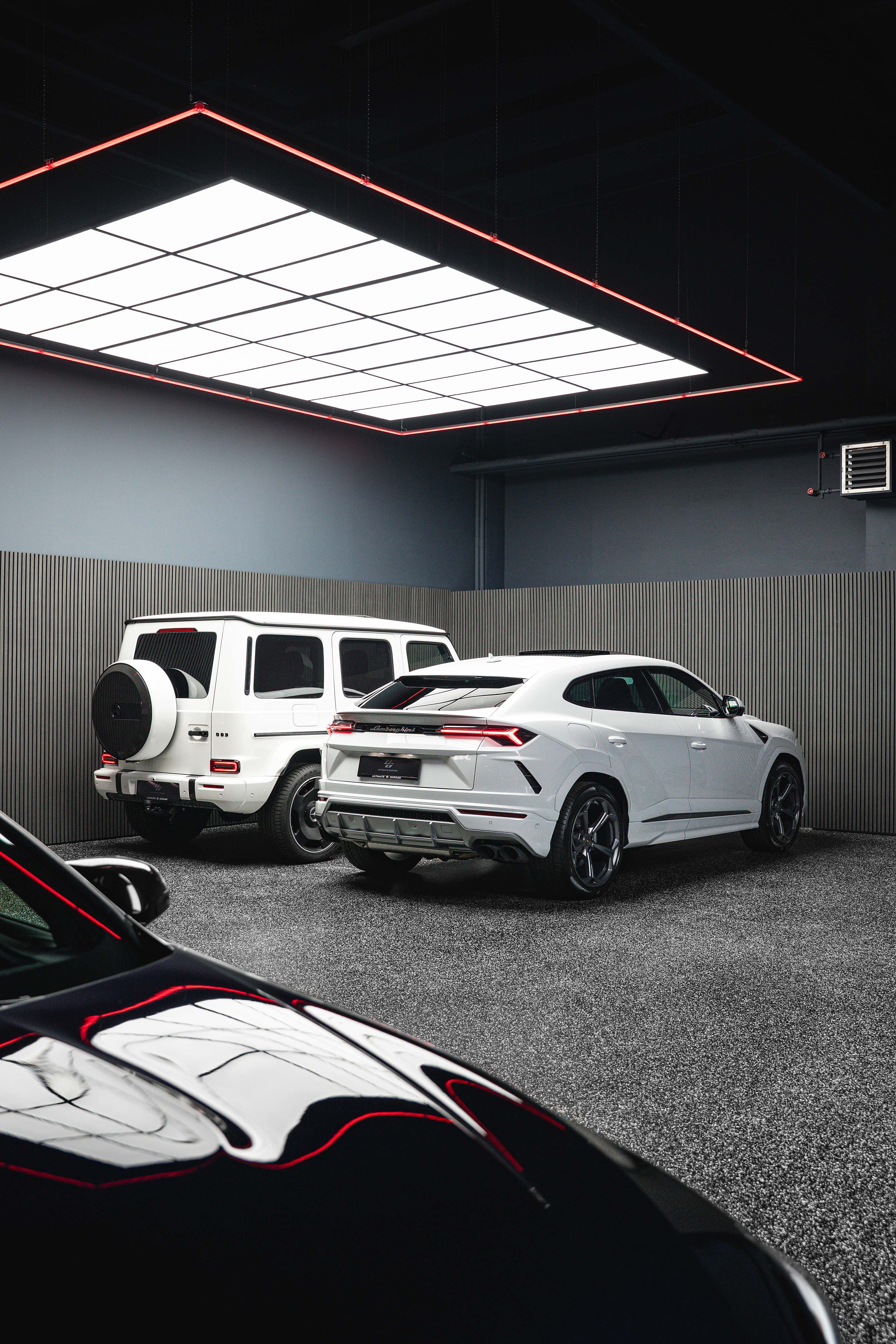 Lamborghini Urus and Mercedes-AMG G 63 under the red light panel in the Ultimate Garage showroom, Sollenau